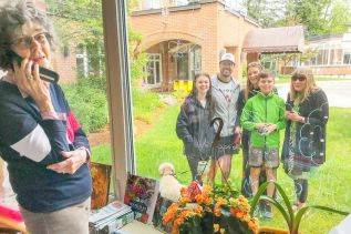 Shirley Hulley, foreground, on the phone with her daughter, Linda Hahn, great grandson Eli, Ms Hulley, granddaughter Jessica, great granddaughter Jessica (who creates the window-drawings) grandson-in-law Don Clowater., and dog Sadie, who is ready to go home. photo supplied by Frontenac County.